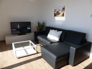 uma sala de estar com um sofá preto e uma televisão em Perla del Lago em Carmine