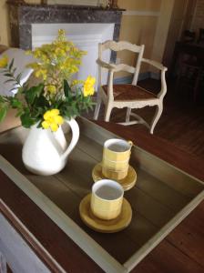 una mesa de centro con dos tazas y un jarrón con flores en Cardabelle Holiday Home with private garden en Mazières