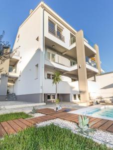 a building with a swimming pool in front of it at Apartmani Pocco Locco in Biograd na Moru