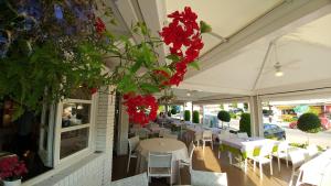 a restaurant with tables and chairs and red flowers at Hotel Ristorante Fortuna in Cavallino-Treporti