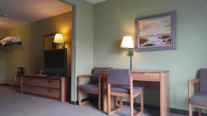 Habitación con 2 sillas, mesa y TV. en Harbor Lights Lodge, en Kewaunee
