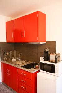 uma cozinha com armários vermelhos, um lavatório e um micro-ondas em Casa do Prado em Vila Verde
