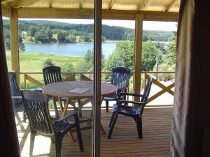 een tafel en stoelen op een veranda met uitzicht op een meer bij Le Chalets du lac de Ganivet in Ribennes +4 foto's