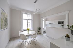 Art Nouveau Residence في براغ: مطبخ أبيض وغرفة طعام مع طاولة بيضاء وكراسي
