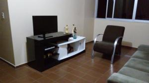 a living room with a flat screen tv and a chair at Ap Acolhedor in Fortaleza