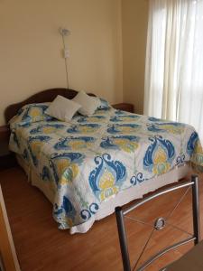 a bed with a blue and white quilt on it at Casa Ananda in Punta de Choros