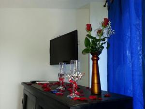 una mesa con un jarrón con rosas y copas de vino en Hotel Katylú, en Tolú
