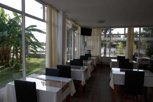un restaurante con mesas y sillas blancas y ventanas en Placeres de la Costa en Gualeguaychú