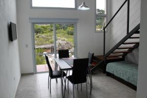 a dining room with a table and chairs and a staircase at Cabañas Paititi in Villa Carlos Paz
