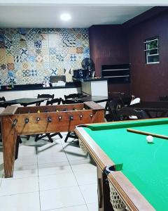 a billiard room with a pool table and a room with chairs at Pousada Nanaco in Garopaba