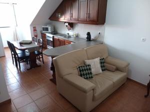 a living room with a couch and a kitchen at Janelas da Praia in Praia da Vitória