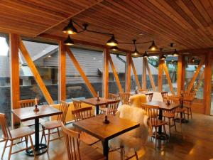 een restaurant met houten tafels, stoelen en ramen bij Hostal Boutique Factoria Patagonia in Puerto Natales