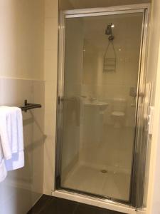 a glass shower in a bathroom with a sink at Lakeside Motel Waterfront in Lakes Entrance
