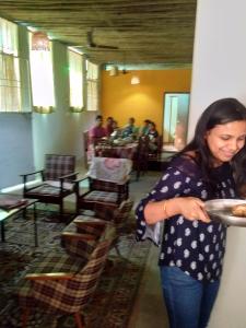 Eine Frau mit einem Teller Essen in einem Zimmer. in der Unterkunft Holiyday in VGF Farm House in Dānishpet