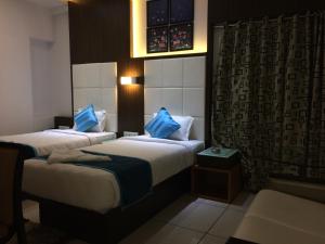 a hotel room with two beds with blue pillows at Hotel Royal Shelter in Vapi +44 photos