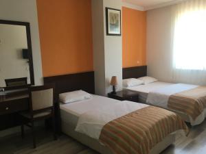 アンタルヤにあるMutado Hotelのベッド2台、デスク、鏡が備わる客室です。