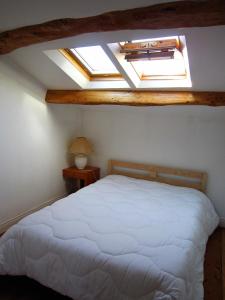 1 Schlafzimmer mit einem weißen Bett und 2 Oberlichtern in der Unterkunft Maison de charme à La Rochelle in Croix-Chapeau