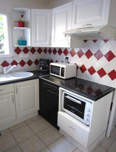 a kitchen with a stove and a microwave at Maison de charme à La Rochelle in Croix-Chapeau