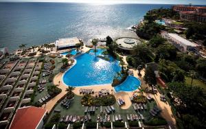 een uitzicht over een zwembad naast de oceaan bij Pestana Carlton Madeira Ocean Resort Hotel in Funchal