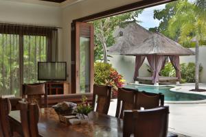 sala de estar con mesa, TV y piscina en Mahagiri Villas & Spa Dreamland, en Uluwatu
