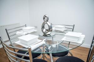 a glass table and chairs with white dishes on it at Luxuriant Apartments in Northampton