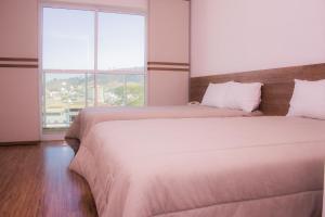 two beds in a room with two large windows at San Marino Hotel in Rio Pomba