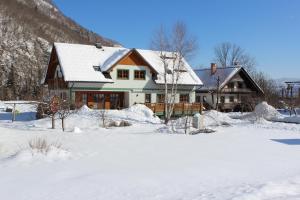 a house with snow on the ground in front of it at Apartments Villa Dov in Bohinj