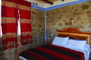 1 dormitorio con 1 cama y 2 cortinas rojas en Gîte El houmar, en Tanakoub