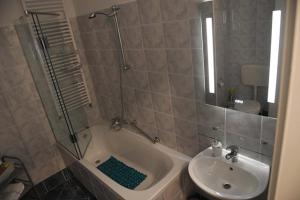 La salle de bains est pourvue d'une douche, d'un lavabo et d'une baignoire. dans l'établissement Oaza Apartman Zagreb Arena, à Zagreb