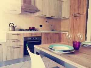 a kitchen with wooden cabinets and a table with plates and wine glasses at Casa Maresole in Diano Marina