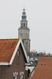 um edifício alto com uma torre de relógio ao fundo em Pied à Terre Oostersingel UMCG em Groningen