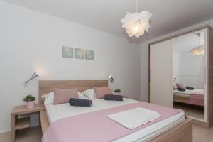 a bedroom with a large white bed and a mirror at Apartmani Pocco Locco in Biograd na Moru