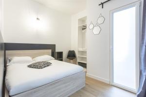 a bedroom with a white bed and a large window at Gare Saint Roch - Podshare in Montpellier