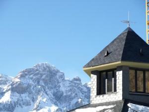 a church with a snow covered mountain in the background at Aparthotel Peña Telera Resort in El Pueyo de Jaca