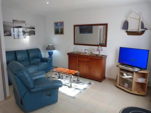 Les Gîtes Bleus de Lannion - avec cuisine- في لانيون: غرفة معيشة مع أريكة زرقاء وتلفزيون
