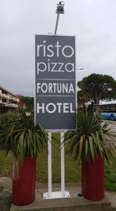 a sign for a hotel next to two potted plants at Hotel Ristorante Fortuna in Cavallino-Treporti