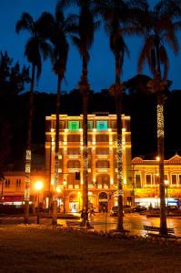 a building with palm trees in front of it at night at Grande Hotel Petrópolis in Petrópolis