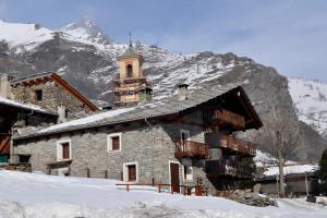 un edificio con una torre dell'orologio nella neve di L'Enventoour a Meleze