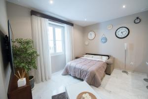 1 dormitorio con 1 cama y reloj en la pared en Sagasta 13 en Cádiz