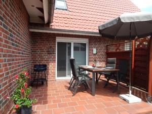 a patio with an umbrella and a table and chairs at Ferienhaus Renate in Leer