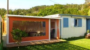 a small house with an orange and white exterior at Bonito bungalow con jardín en playa Nerga in Hio +10 photos