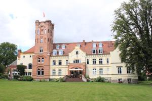 ein großes Gebäude mit einem Turm auf einem Feld in der Unterkunft Schloss Lelkendorf - Fewo Prebberede in Lelkendorf