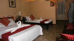 a hotel room with two beds with red and white sheets at Adventure Camp Beach Resort in Sablayan