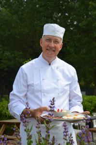 a man in a chefs hat holding a plate of food at Affittacamere Porticciolo in Castelnuovo del Garda