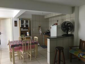 eine Küche mit einem Tisch und Stühlen sowie einem Kühlschrank in der Unterkunft Canto da Praia in Itajubá