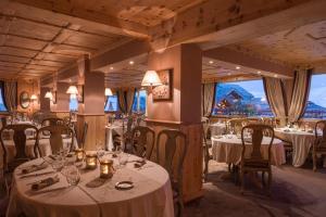 a restaurant with white tables and chairs and large windows at Hôtel Au Chamois d'Or by Les Etincelles in L'Alpe-d'Huez
