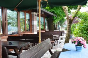 a patio with benches and tables and an umbrella at Affittacamere Porticciolo in Castelnuovo del Garda