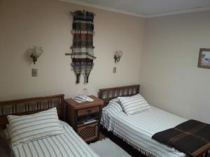 a bedroom with two beds and a night stand and two lamps at Hotel Boutique Las Azucenas in Constitución