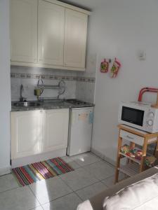 a kitchen with white cabinets and a sink and a microwave at Apartamento privado con piscina in Costa Del Silencio