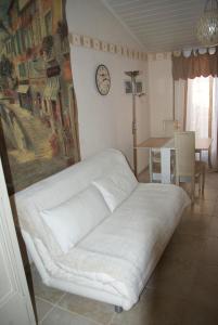 a white couch in a room with a clock on the wall at B&B Villa Viva Vitale in Pierrevert